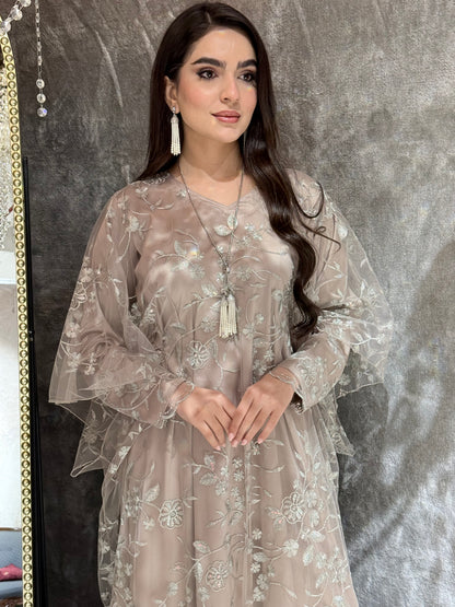Woman in a Dusty Beige Floral Embroidered Kaftan standing in front of a mirror with a chandelier in the background
