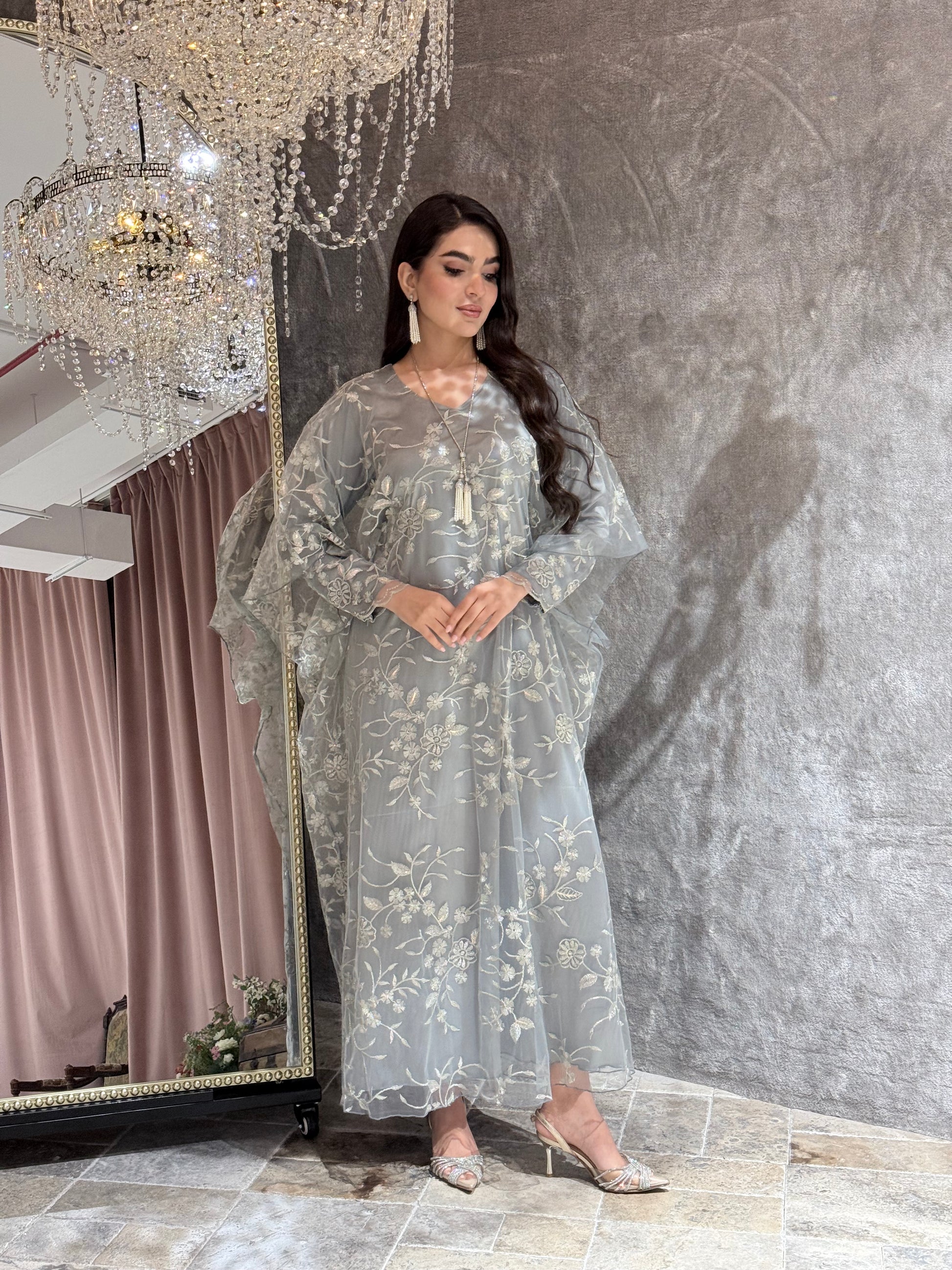 Woman in a Silver Grey Floral Embroidered Kaftan lying on a textured gray surface