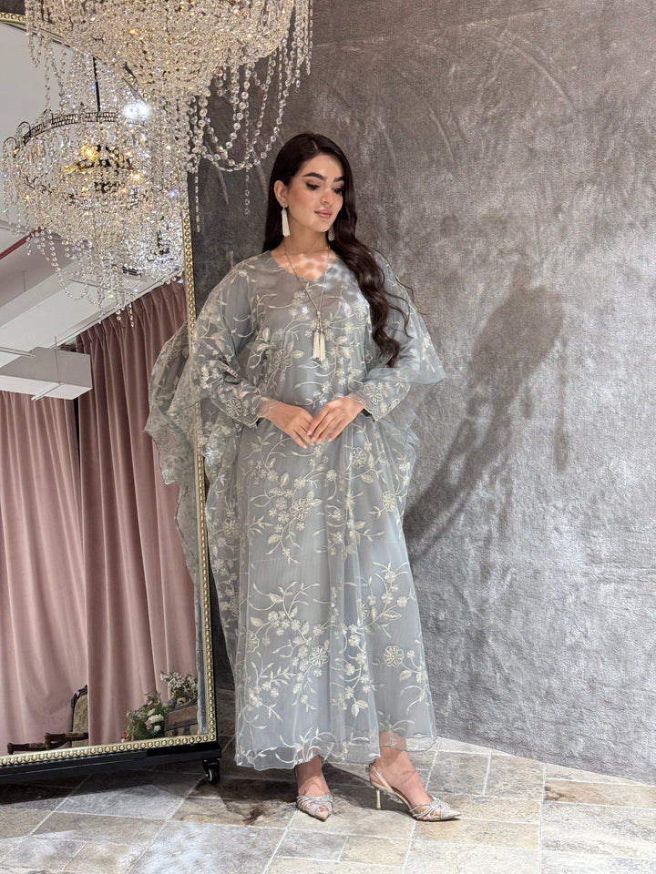 Woman in a Silver Grey Floral Embroidered Kaftan lying on a textured gray surface