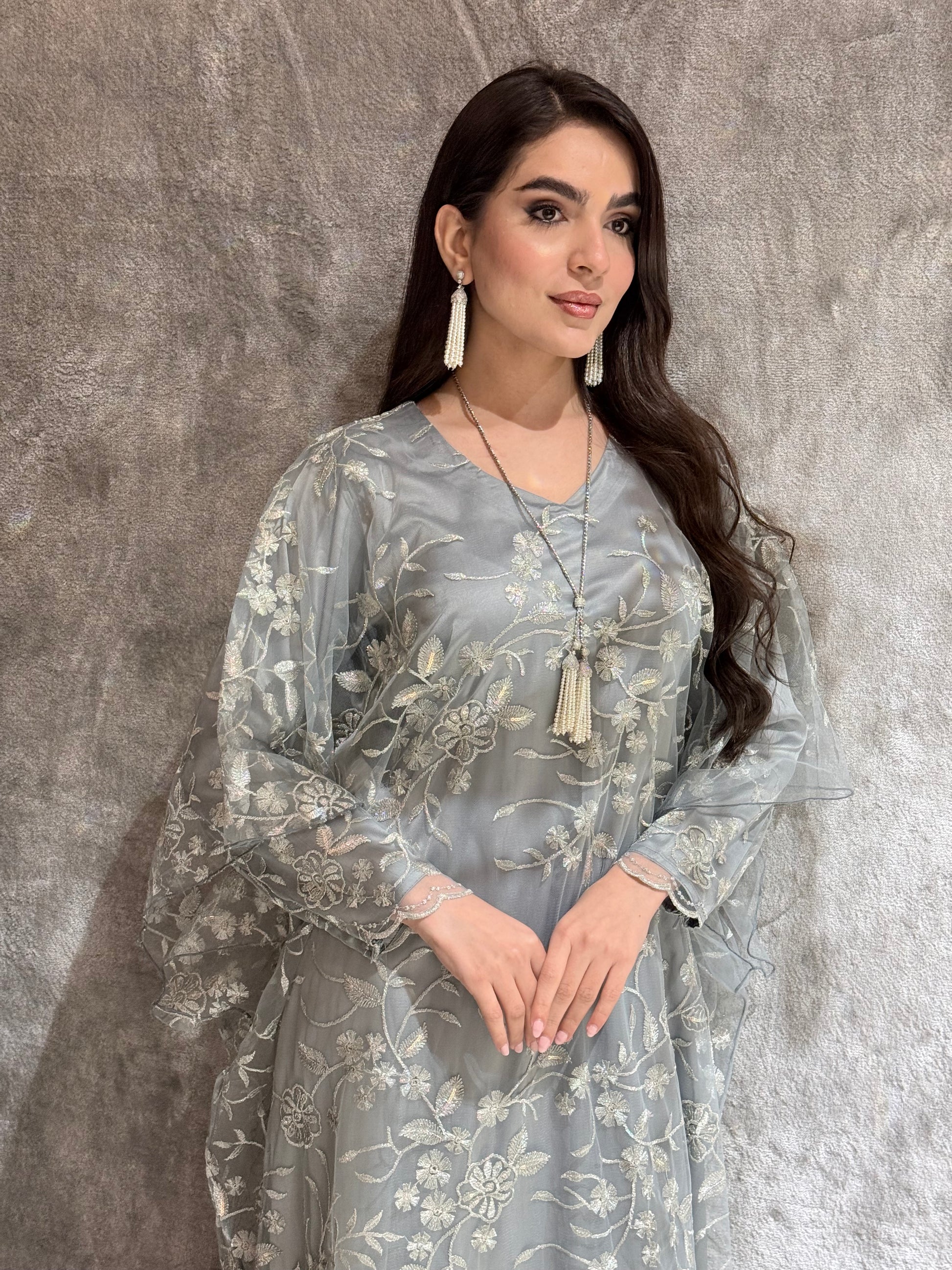 Woman in a Silver Grey Floral Embroidered Kaftan lying on a textured gray surface
