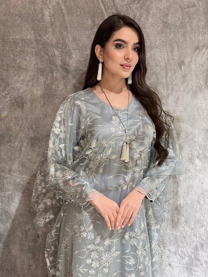 Woman in a Silver Grey Floral Embroidered Kaftan lying on a textured gray surface