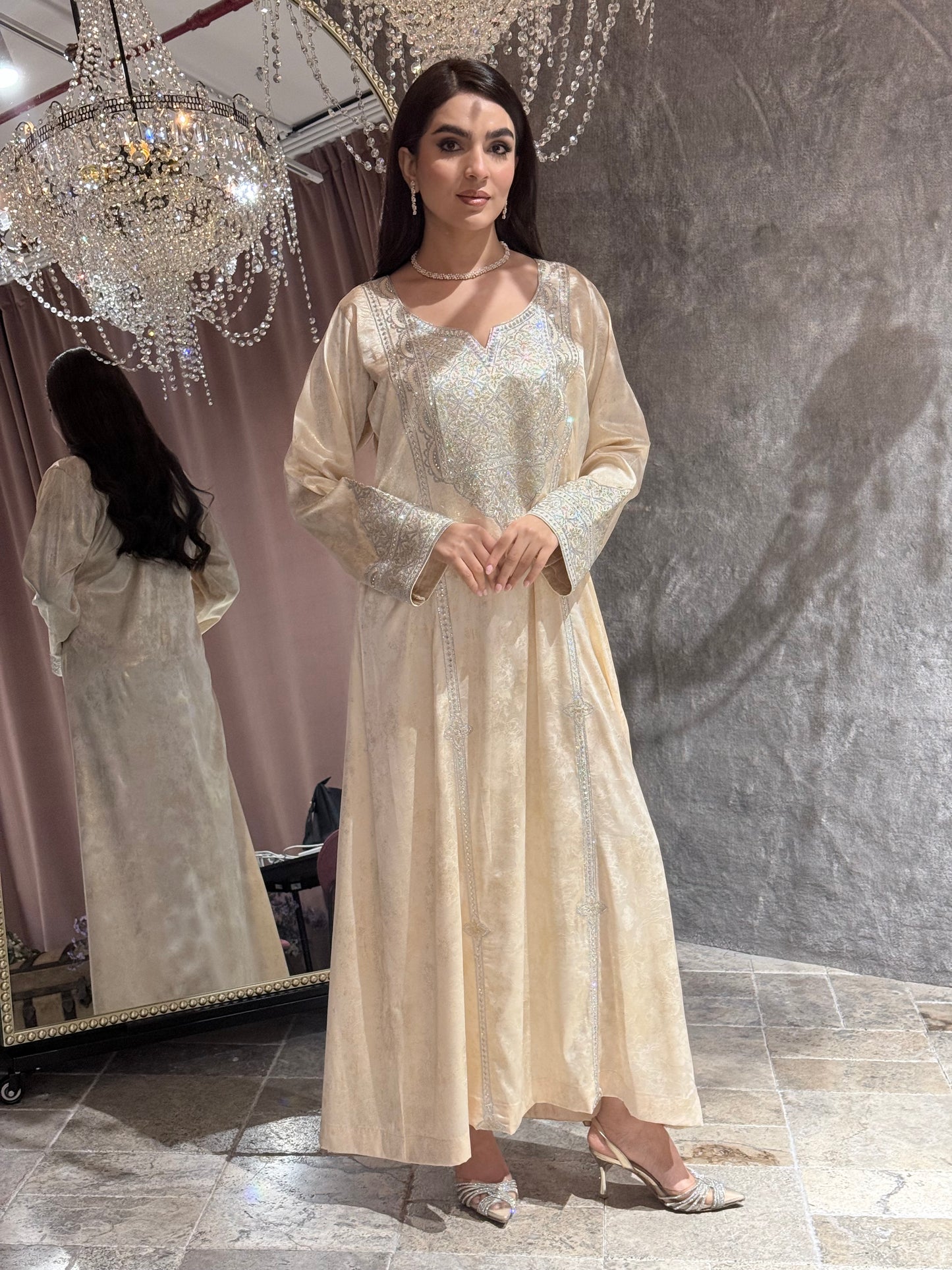 Woman in a long, elegant Cream Metallic Luxury Kaftan dress standing in front of a mirror.