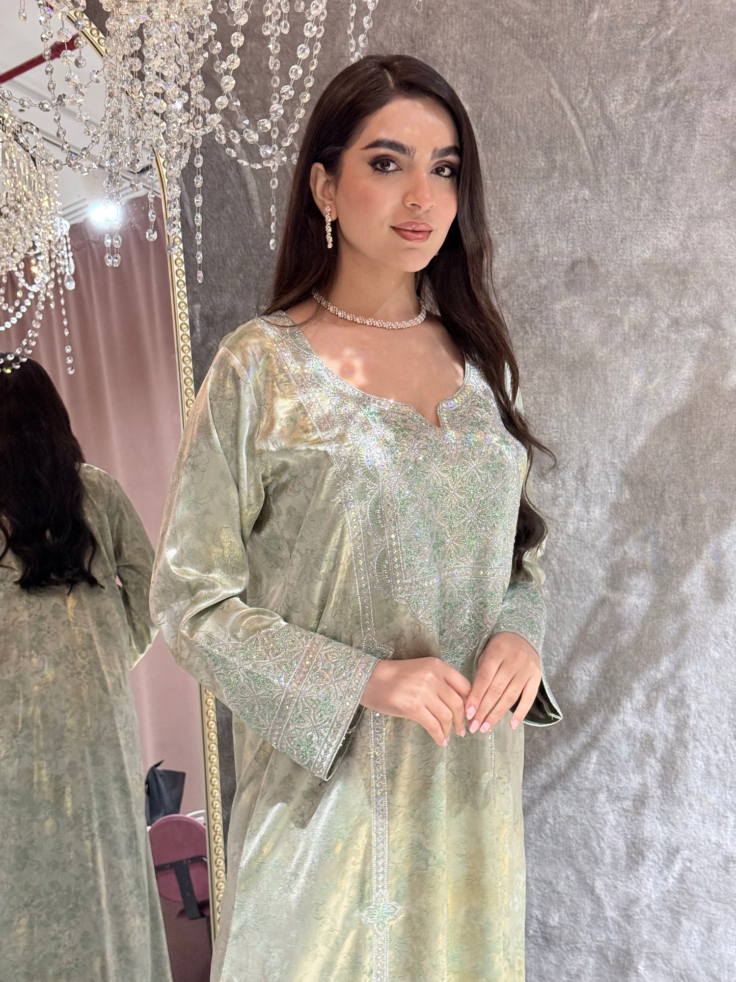 Woman in a sparkling Mint Green Metallic Luxury Kaftan dress standing against a reflective surface.