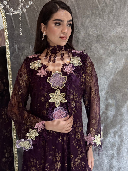 Woman in a Dark Purple Floral Lace Luxury Kaftan dress with floral embellishments lying on a textured surface.