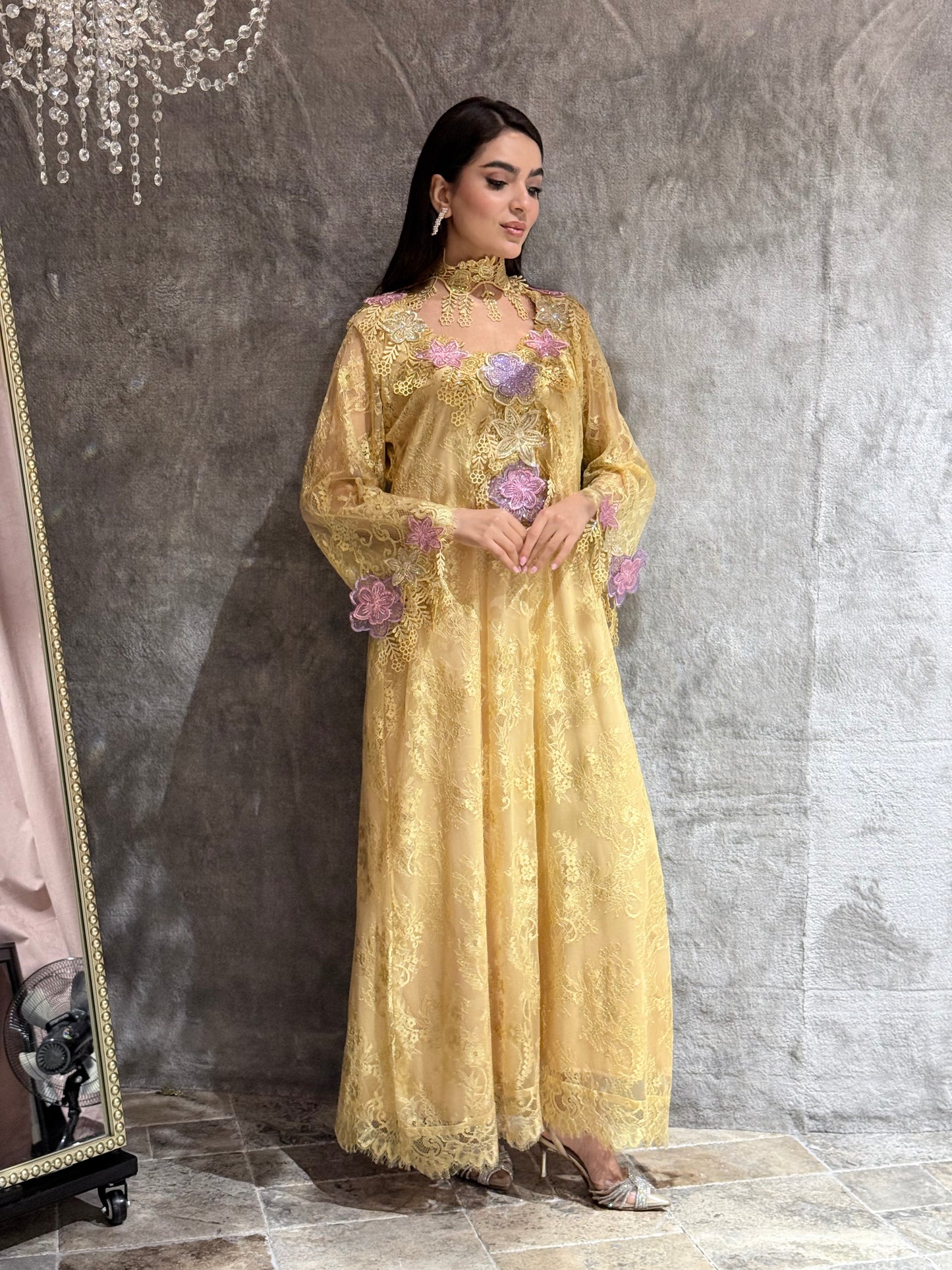 Woman in a Golden Saffron Floral Lace Luxury Kaftan dress standing on a reflective floor.