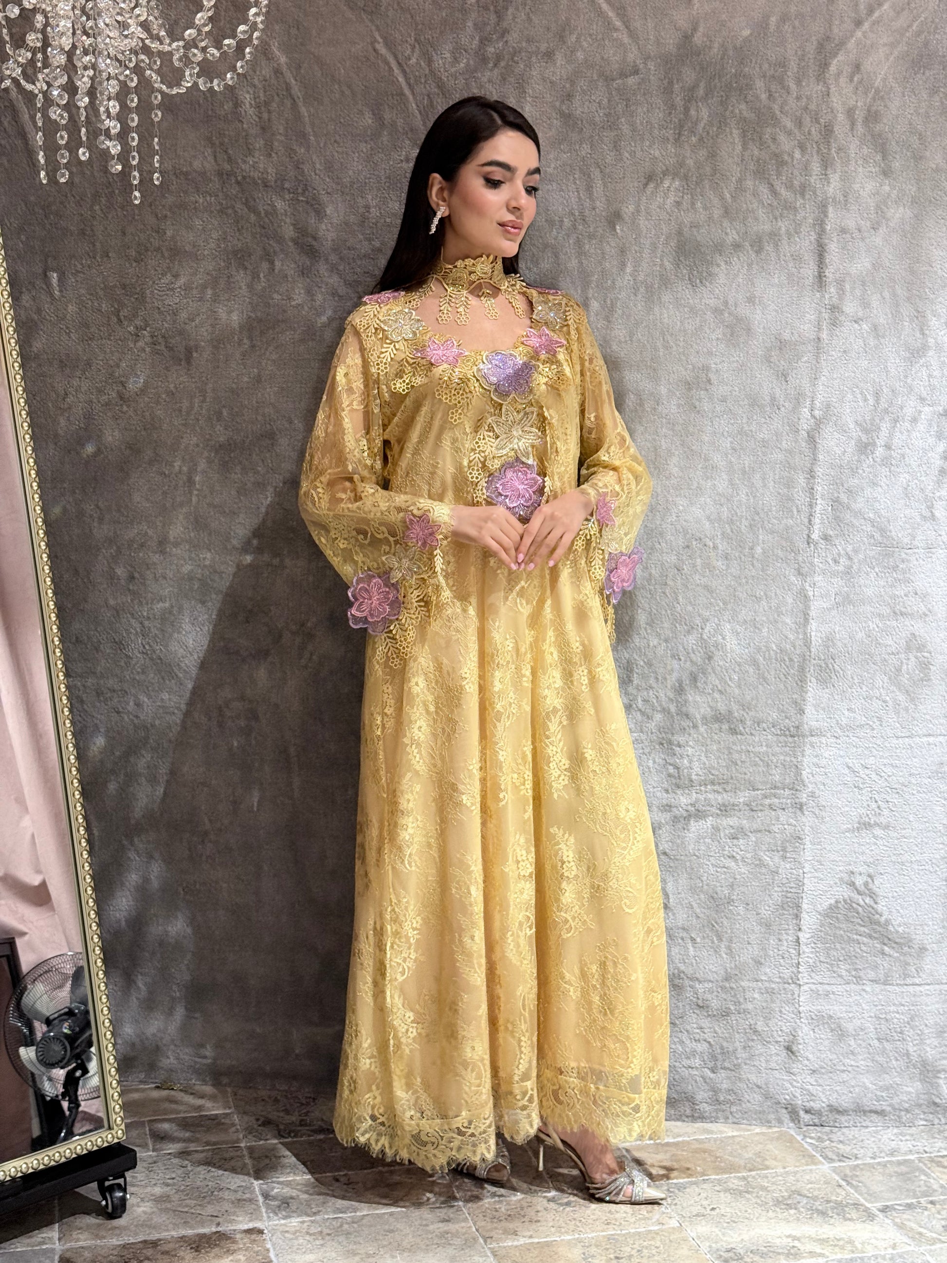 Woman in a Golden Saffron Floral Lace Luxury Kaftan dress standing on a reflective floor.