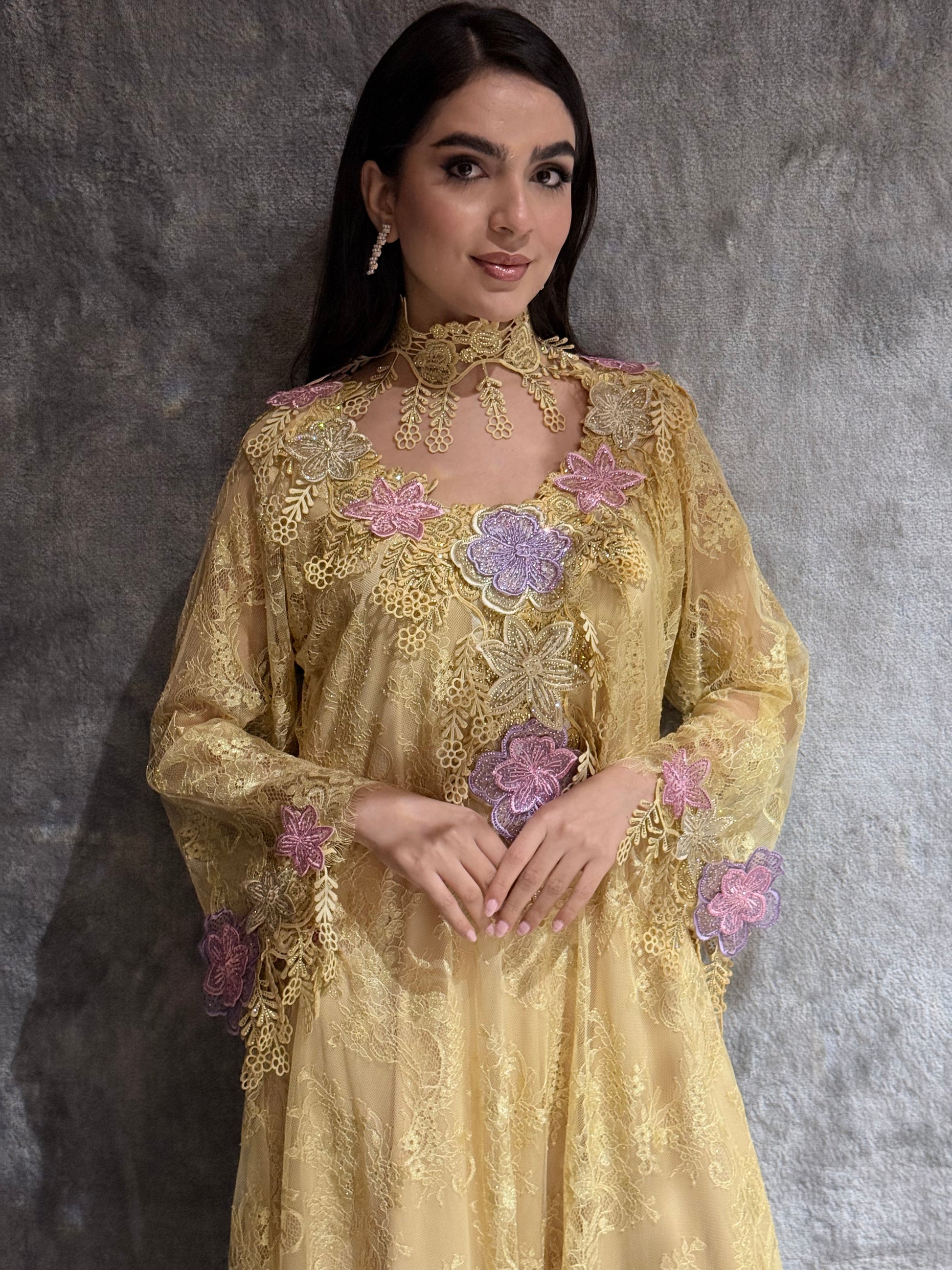 Woman wearing a Golden Saffron Floral Lace Luxury Kaftan embroidered dress with floral patterns on a gray background