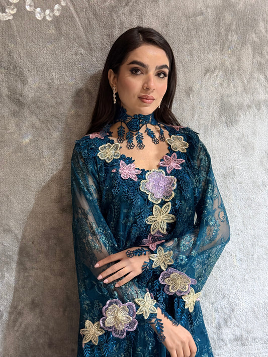 Woman in a Majestic Teal Floral Lace Luxury Kaftan  floral embroidered dress lying on a textured surface