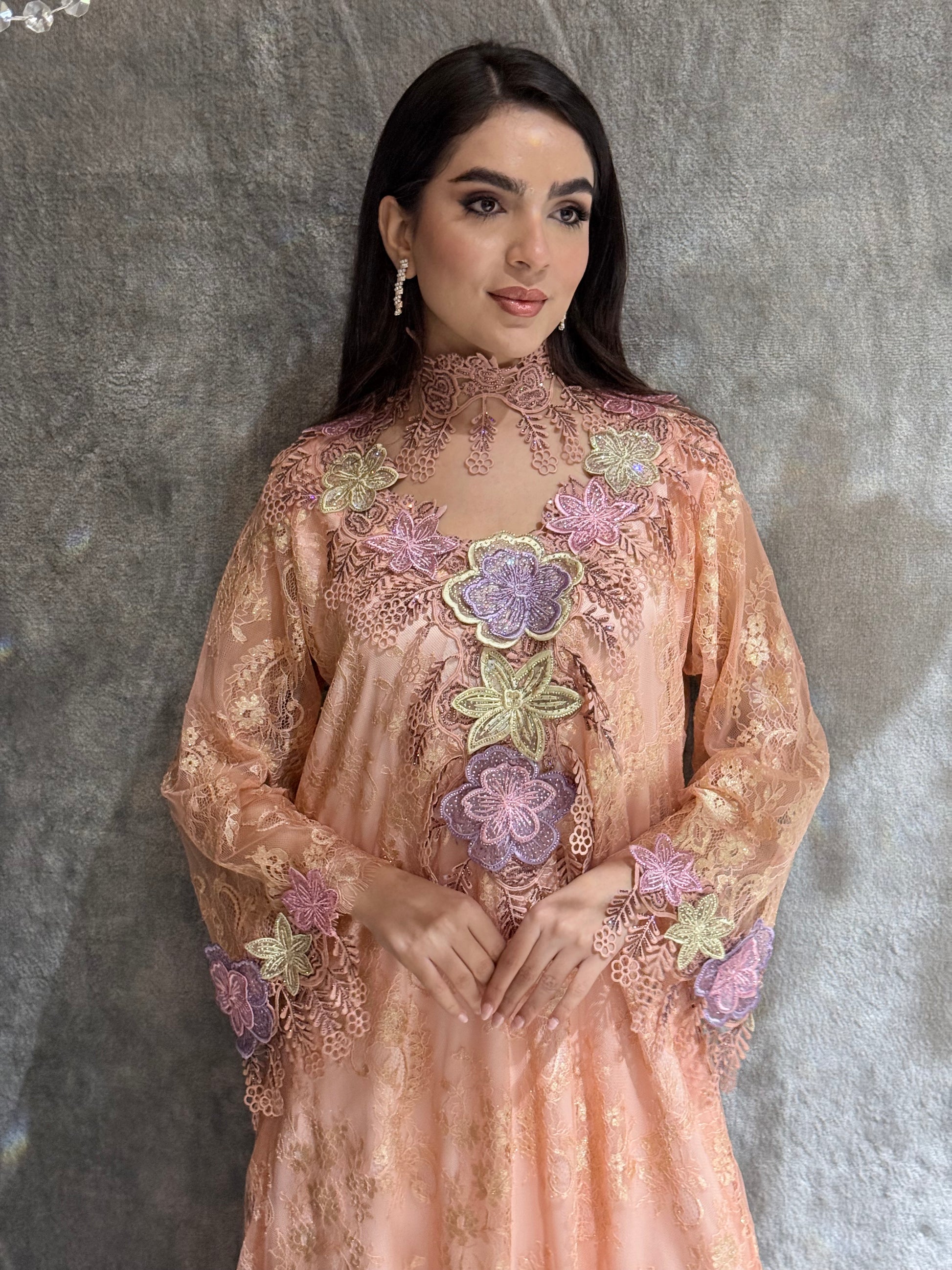 Woman in a Peach Floral Lace Luxury Kaftan dress lying on a gray textured surface