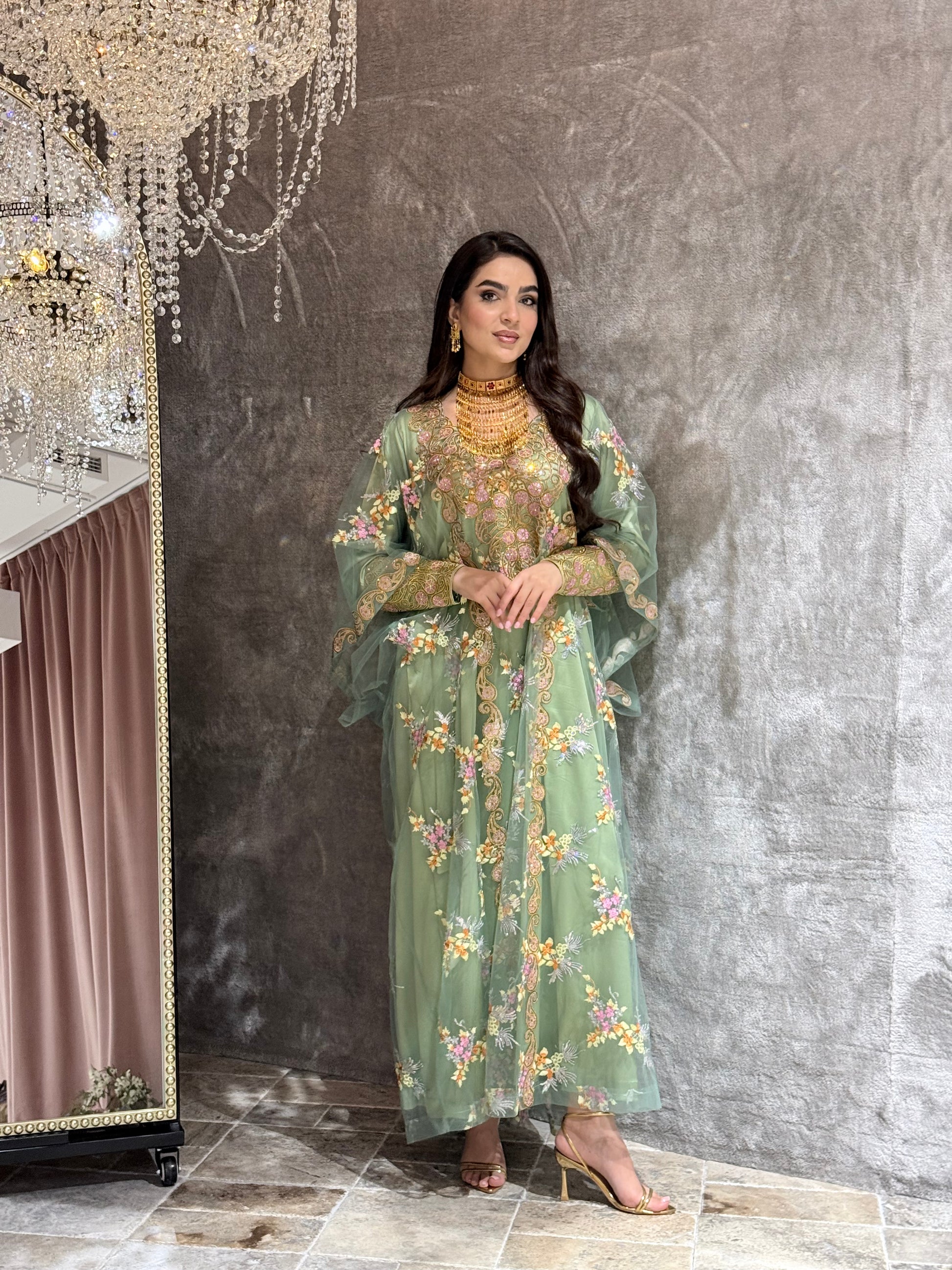 Woman in a Mint Green Luxury Kaftan dress standing against a textured wall.