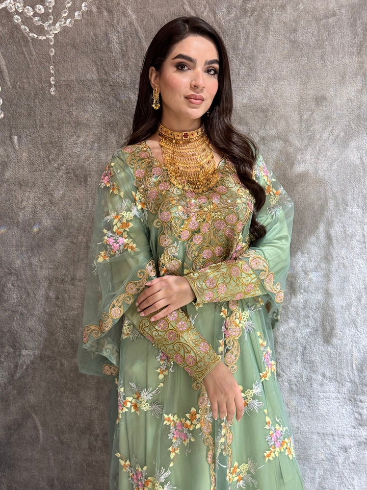 Woman in a Mint Green Luxury Kaftan dress standing against a textured wall.