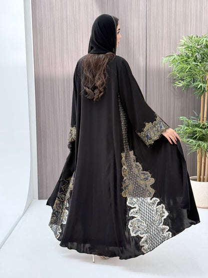 a woman wearing an elegant open-front black abaya featuring intricate multi-colored beadwork, sequins, and metallic embroidery in an indoor setting.