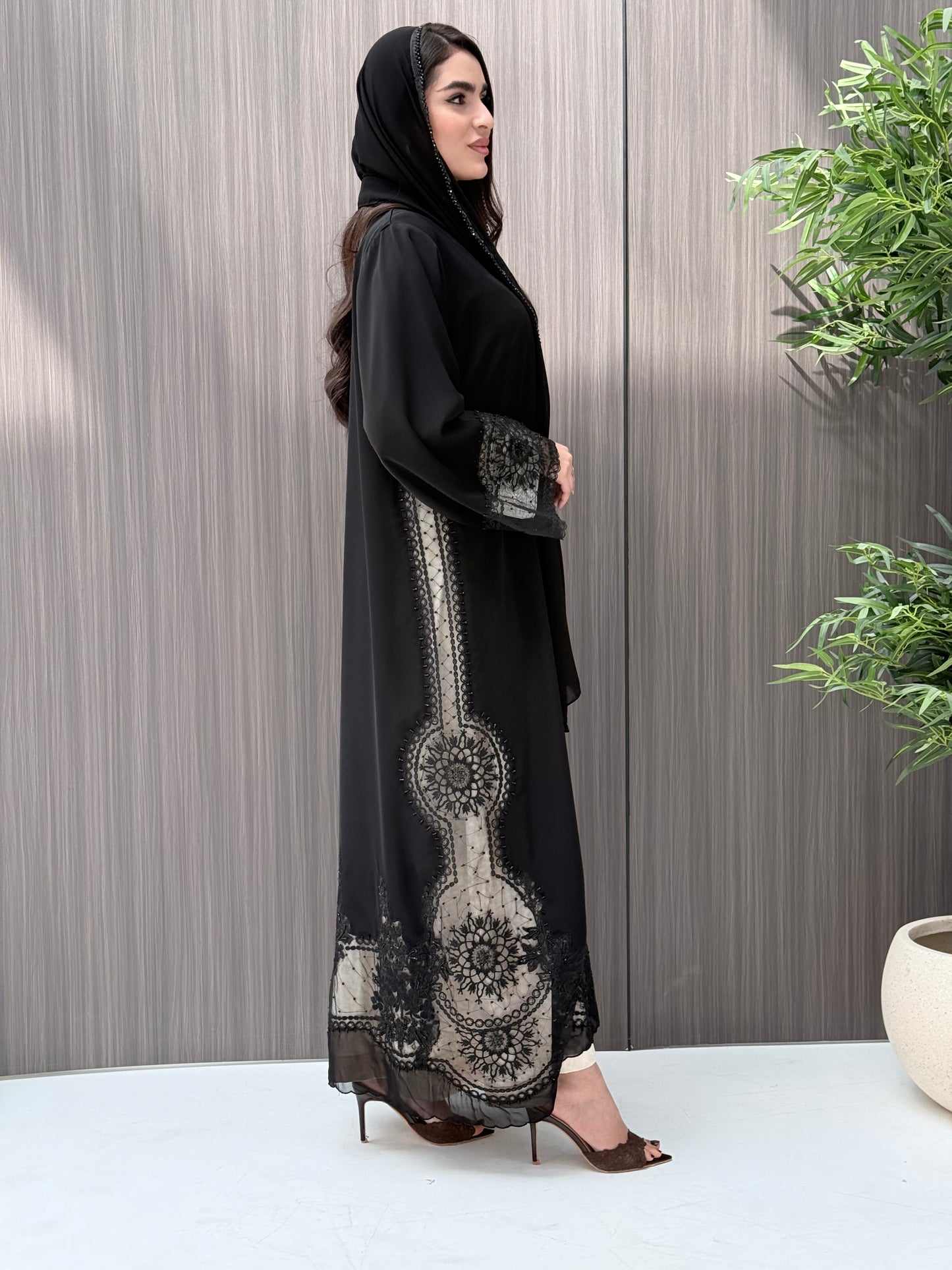 Woman wearing a luxury open-front black abaya crafted from premium Nida fabric with matching sheila standing indoor