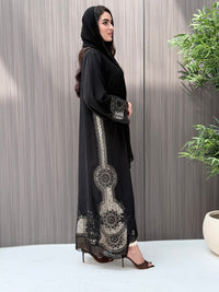 Woman wearing a luxury open-front black abaya crafted from premium Nida fabric with matching sheila standing indoor