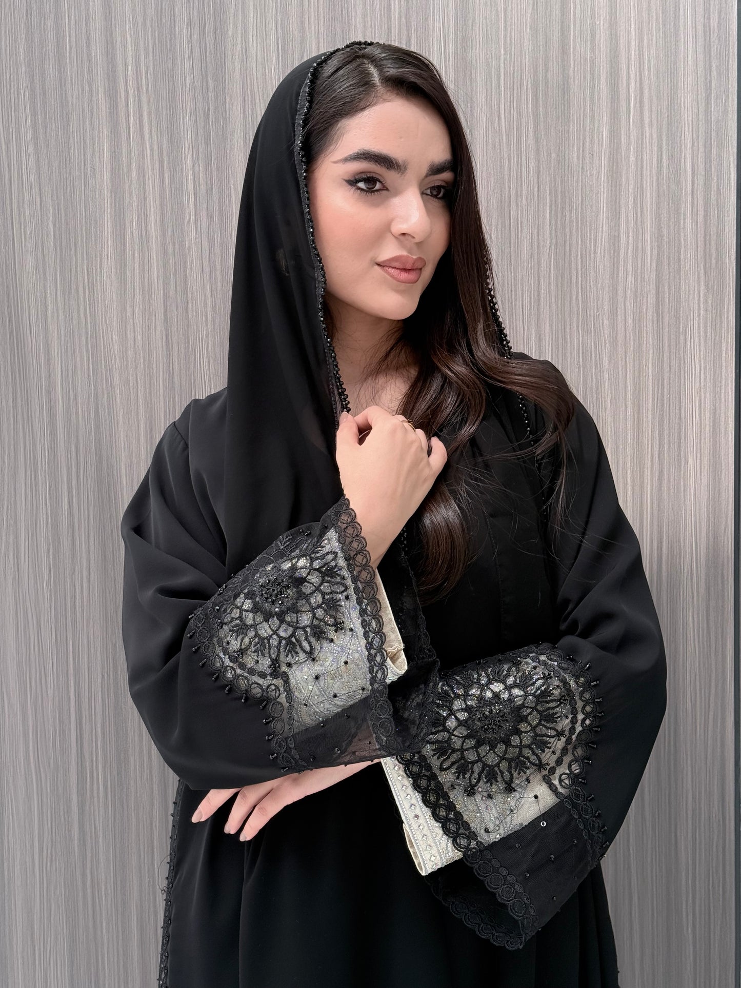 Woman wearing a luxury open-front black abaya crafted from premium Nida fabric with matching sheila on a gray background