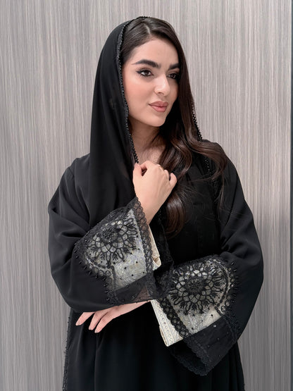 Woman wearing a luxury open-front black abaya crafted from premium Nida fabric with matching sheila on a gray background