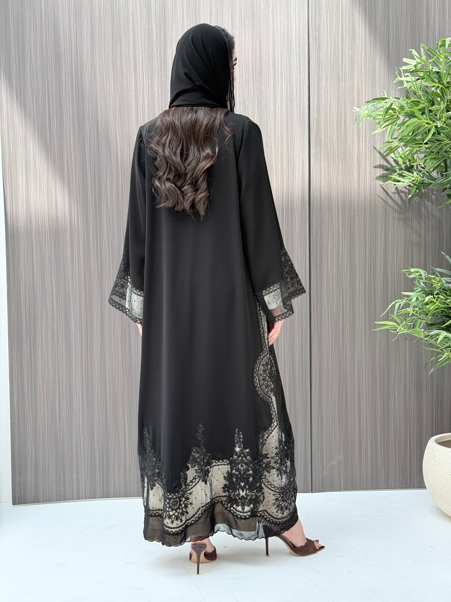 Woman wearing a luxury open-front black abaya crafted from premium Nida fabric with matching sheila on a gray background