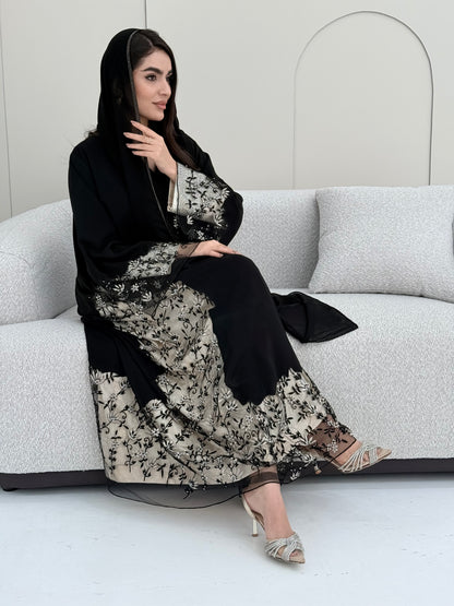 Woman wearing an elegant luxury open-front black abaya crafted from premium Nida fabric with a matching sheila.
 on a white background