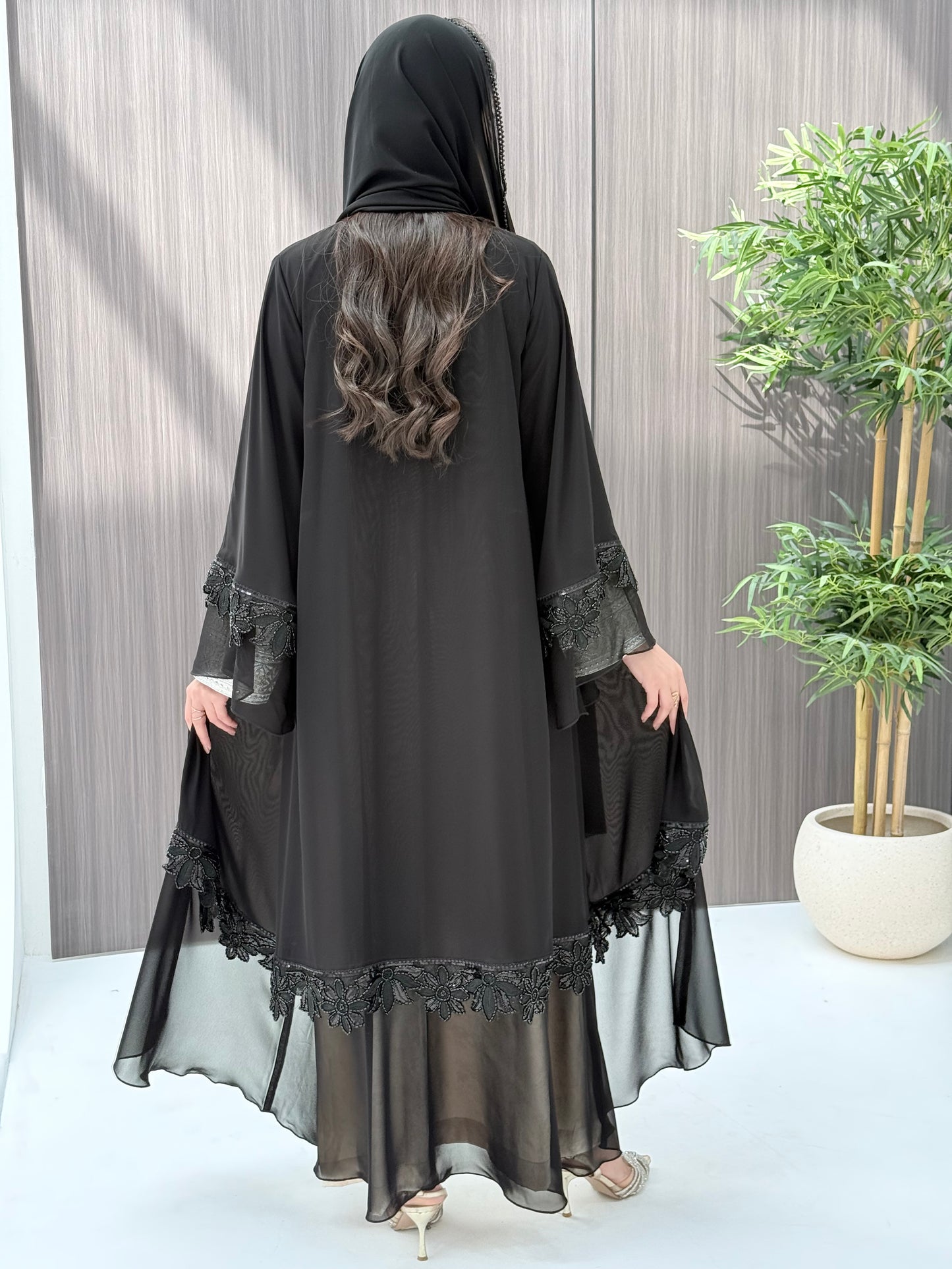 a woman wearing Black abaya with floral embroidery on a wooden floor