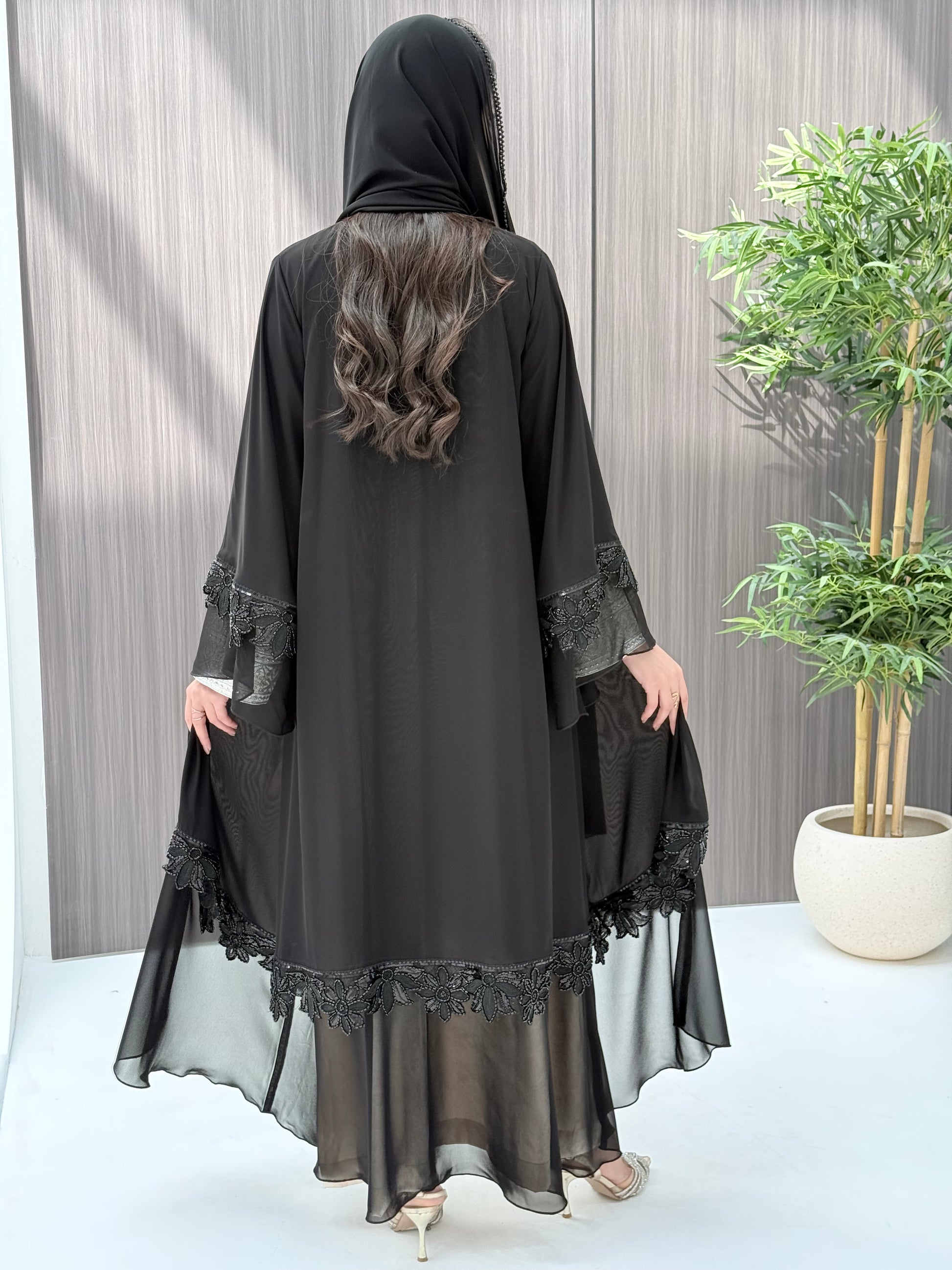 a woman wearing Black abaya with floral embroidery on a wooden floor