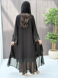 a woman wearing Black abaya with floral embroidery on a wooden floor