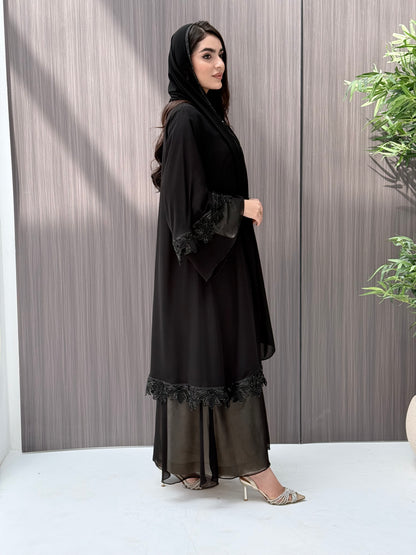 Woman wearing a black abaya standing on a wooden floor.
