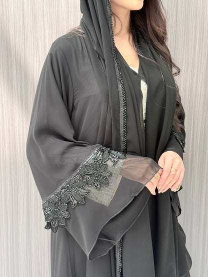 a woman wearing Black Beaded Floral Open Front Abaya in an indoor environment with matching sheila