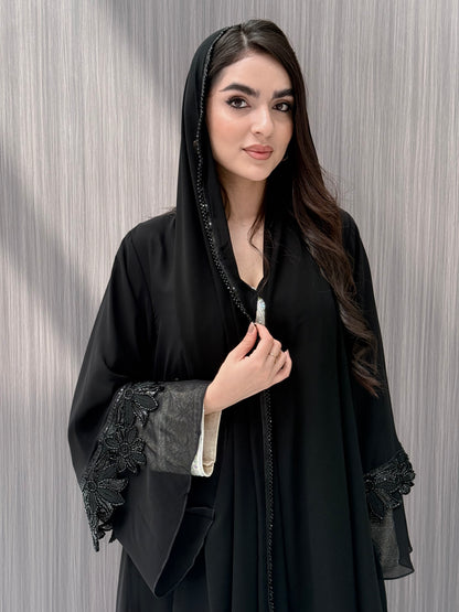 Woman wearing a Black Beaded Floral Open Front Abaya with matching sheila on a  gray background