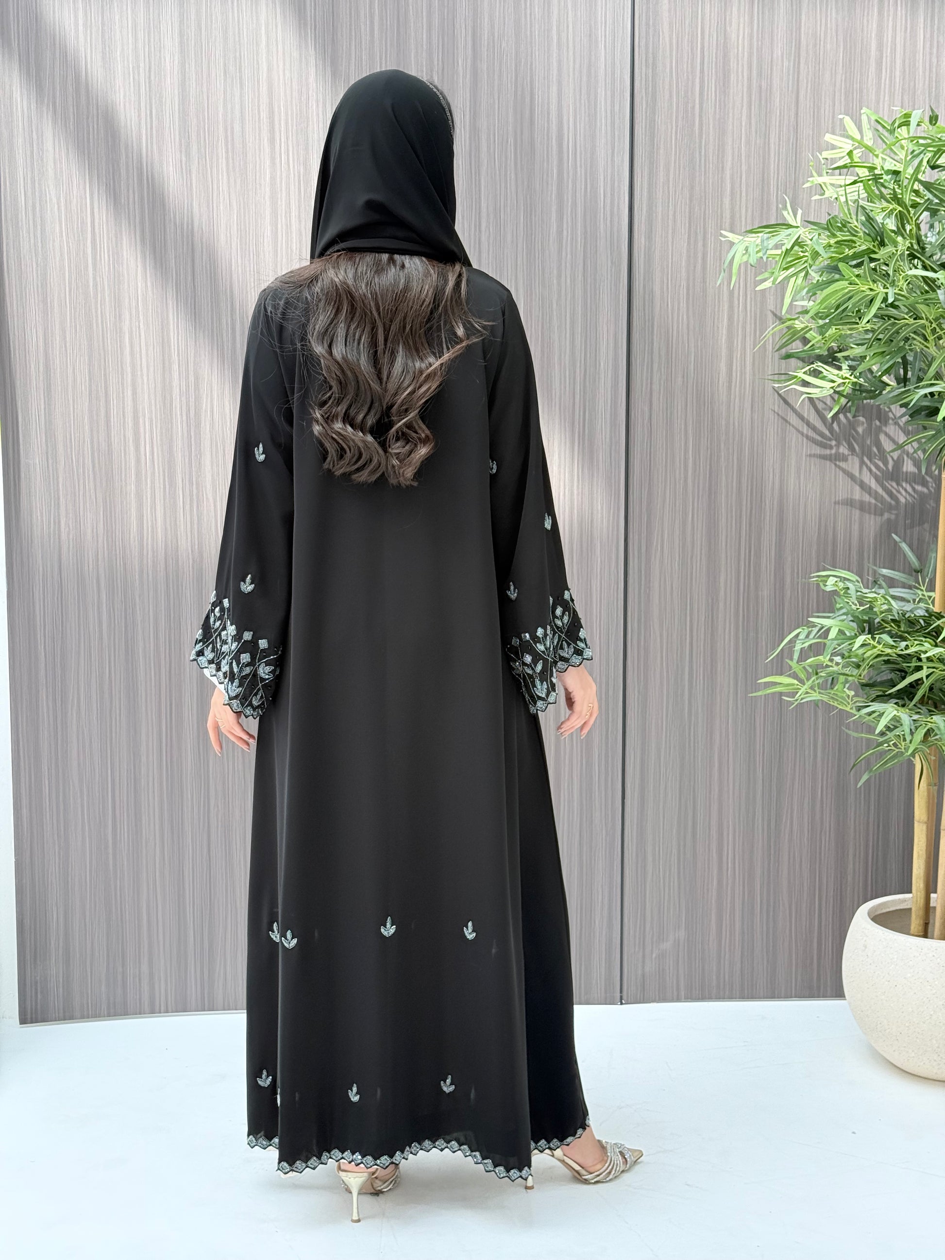 A woman wearing a black embroidered floral open abaya, which is perfect for ceremonies, Eid, and parties.