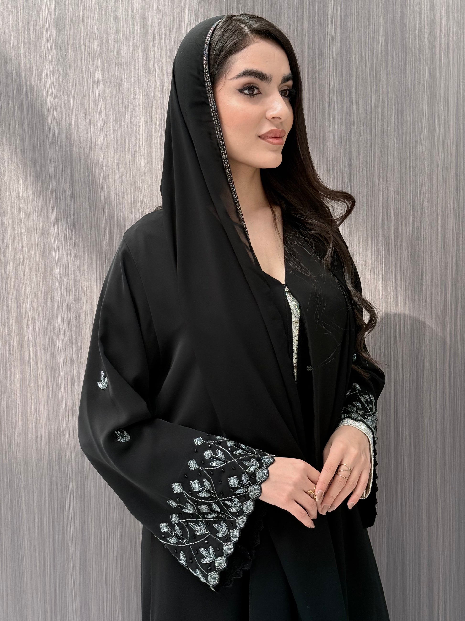 A woman wearing a black embroidered floral open abaya, which is perfect for ceremonies, Eid, and parties.