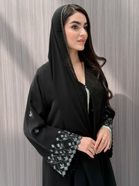 A woman wearing a black embroidered floral open abaya, which is perfect for ceremonies, Eid, and parties.