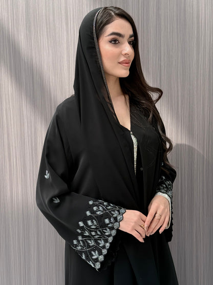 A woman wearing a black embroidered floral open abaya, which is perfect for ceremonies, Eid, and parties.