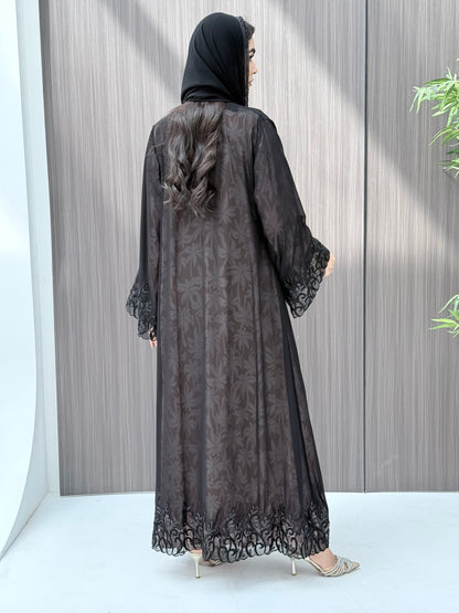 Woman wearing an open-front sheer black abaya with a matching beaded sheila on a gray background