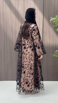 Woman wearing a Black Sheer Floral Appliqué Open Front Abaya with a mathcing sheila against a wooden panel background