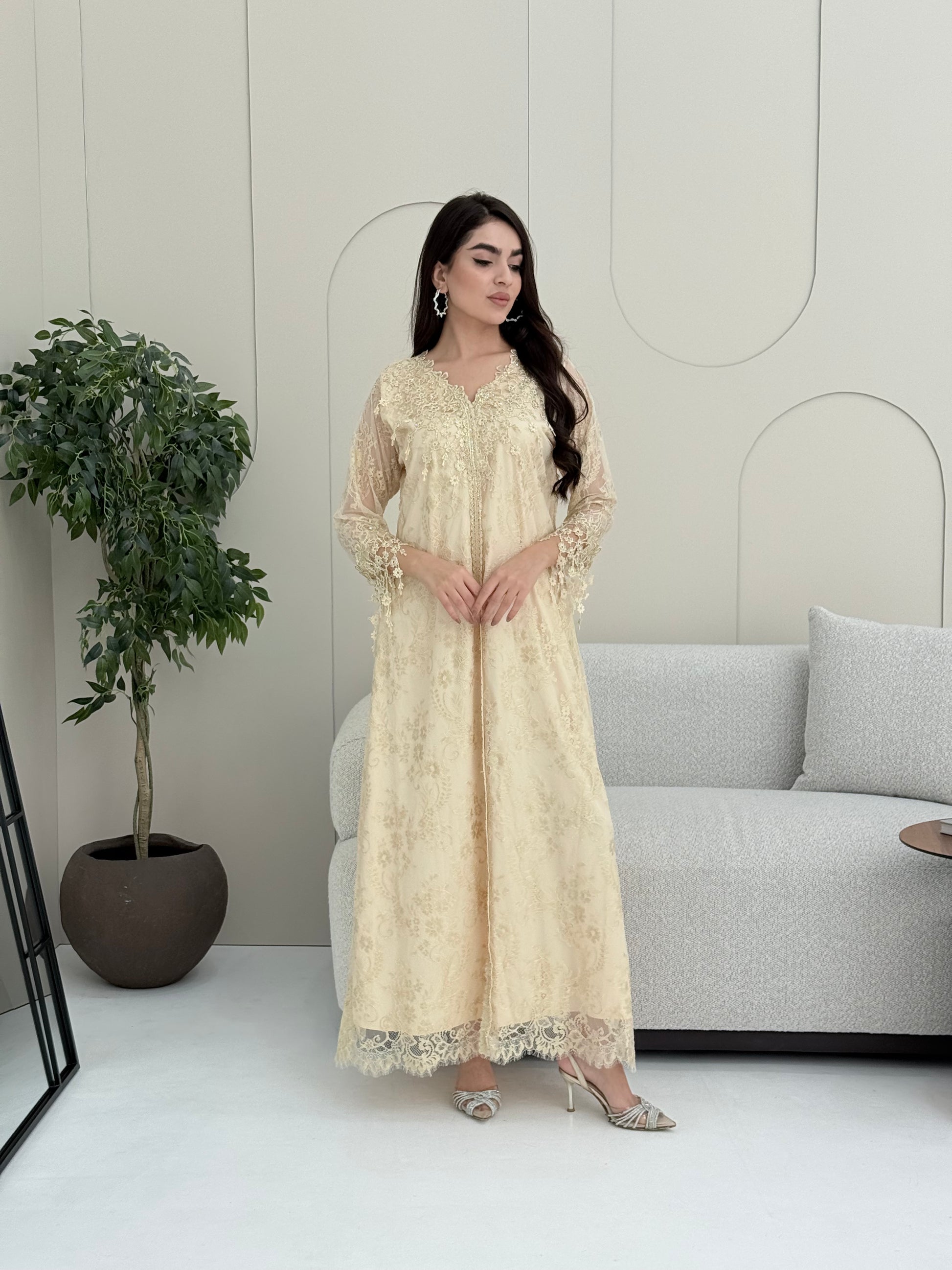 A woman wearing a cream floral lace kaftan, perfect for Eid, luxury occasions and parties.