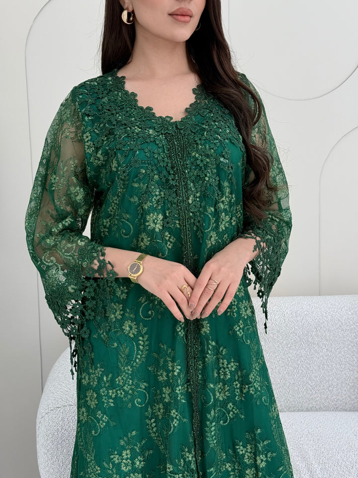A woman wearing an emerald green floral lace kaftan, perfect for Eid, luxury occasions and parties.