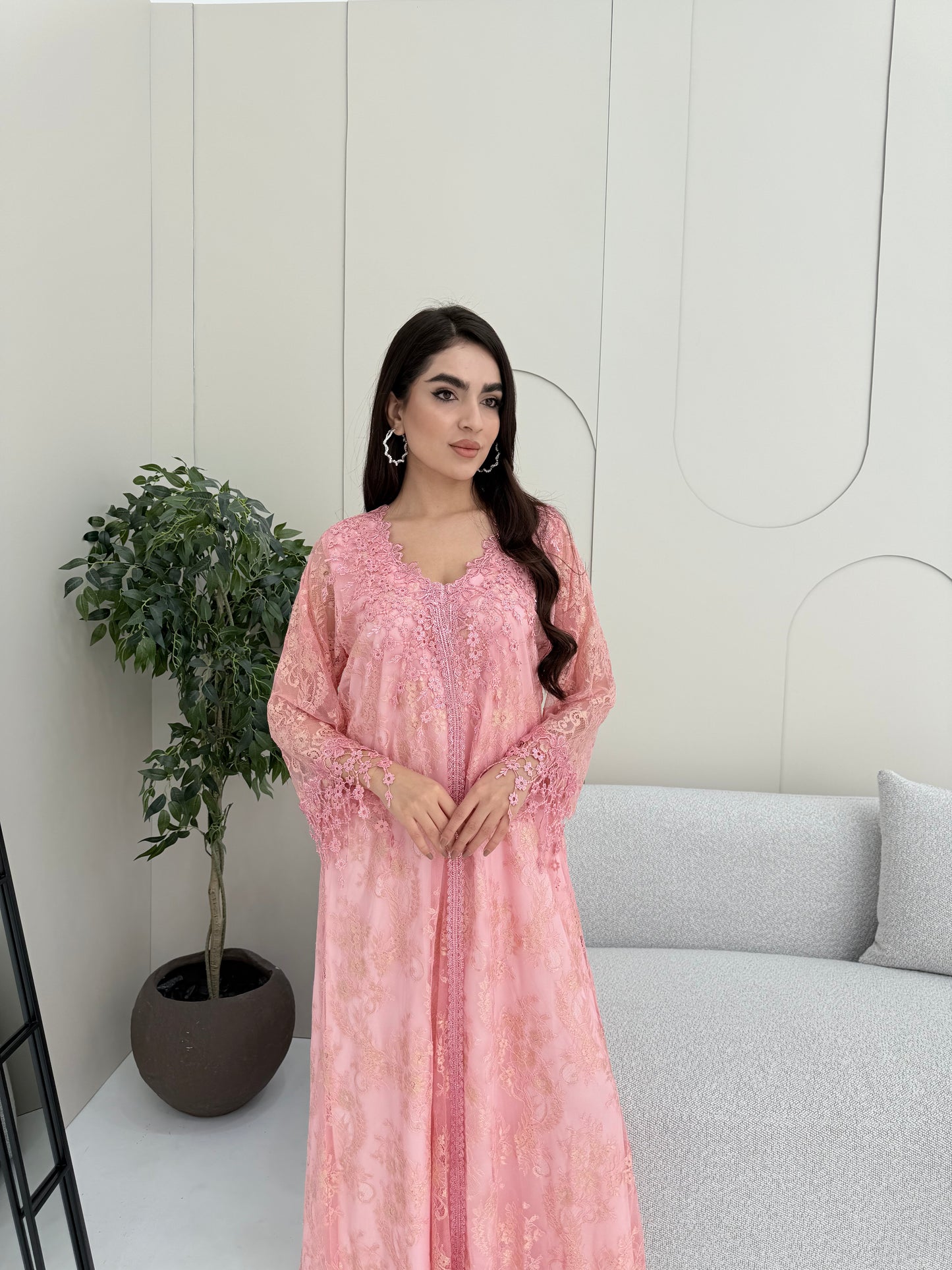 A woman wearing a pink floral lace kaftan, perfect for Eid, luxury occasions and parties.