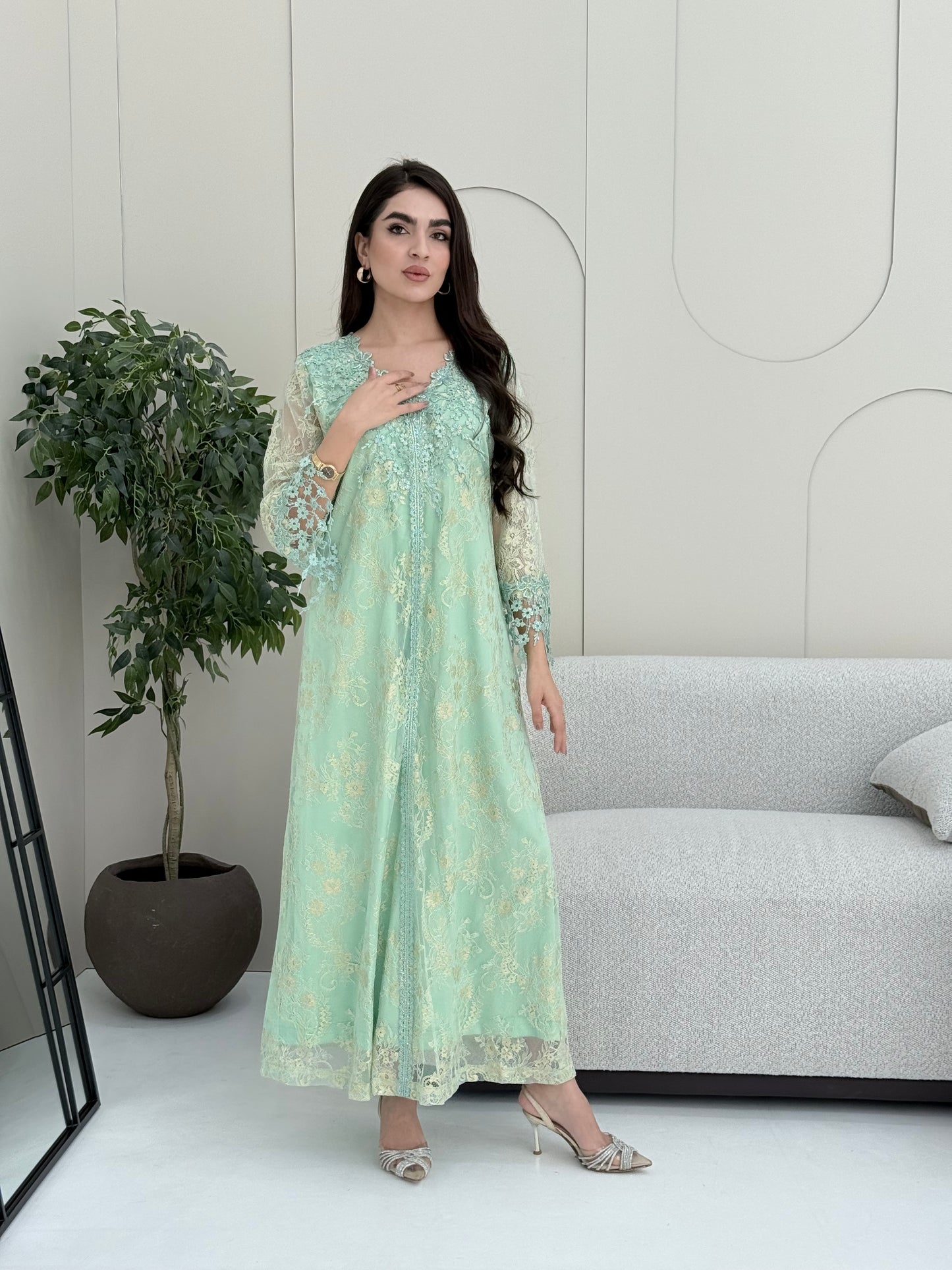 A woman wearing a mint green floral lace kaftan, perfect for Eid, luxury occasions and parties.